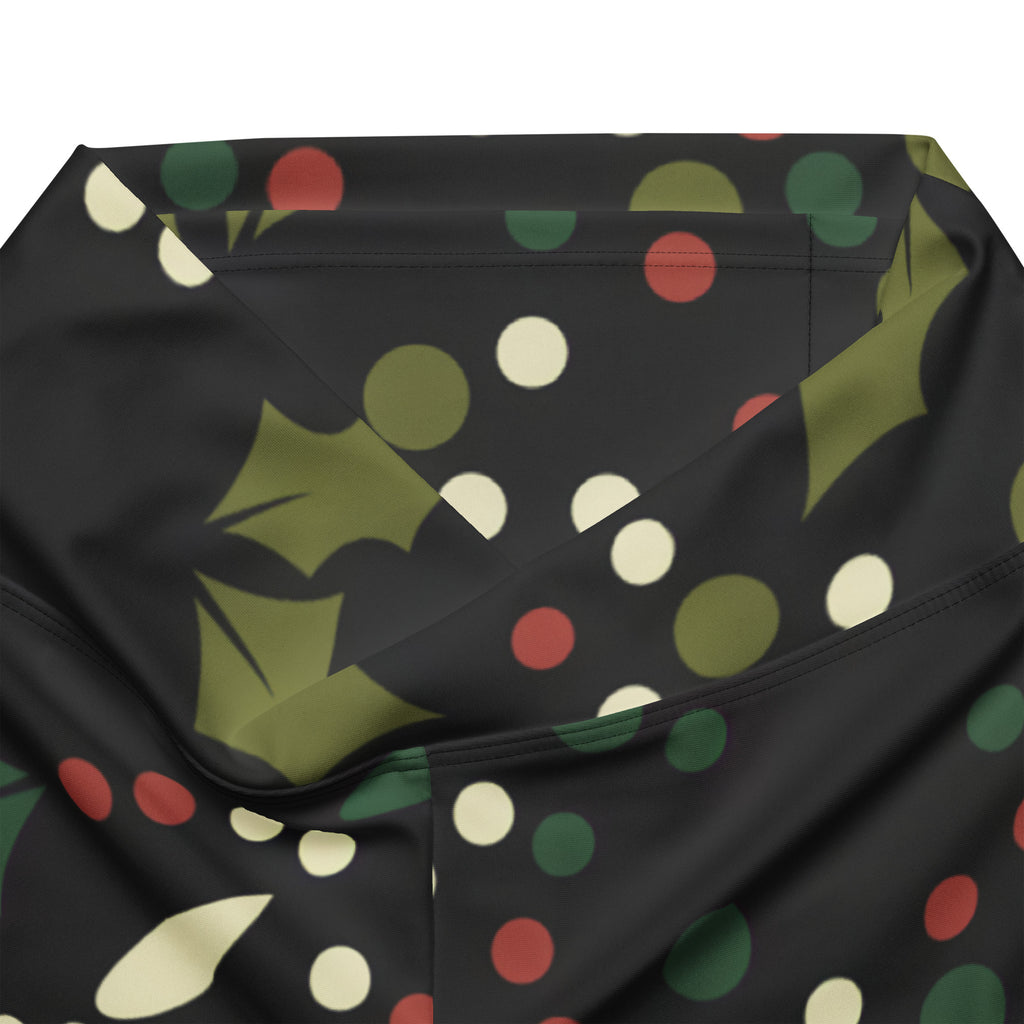 Black women’s high waist flare legging pants with festive green holly leaves and red cream polka dot pattern