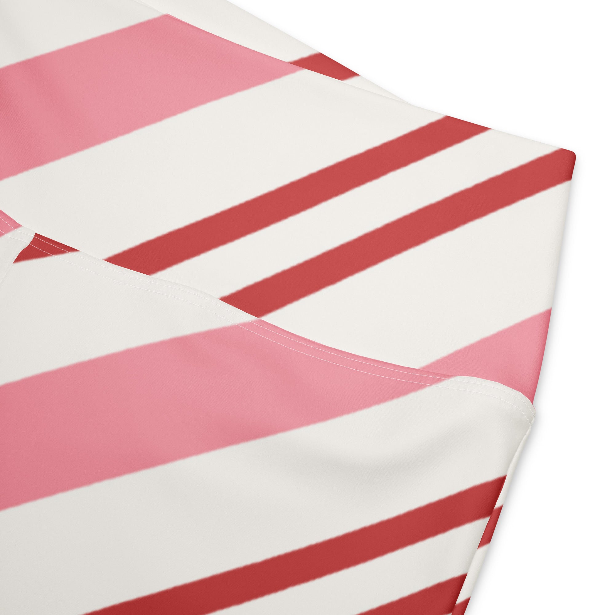 A soft fabric baby changing pad with bold pink and white diagonal stripes paired with women’s pink candy cane stripes high waist flare legging pants