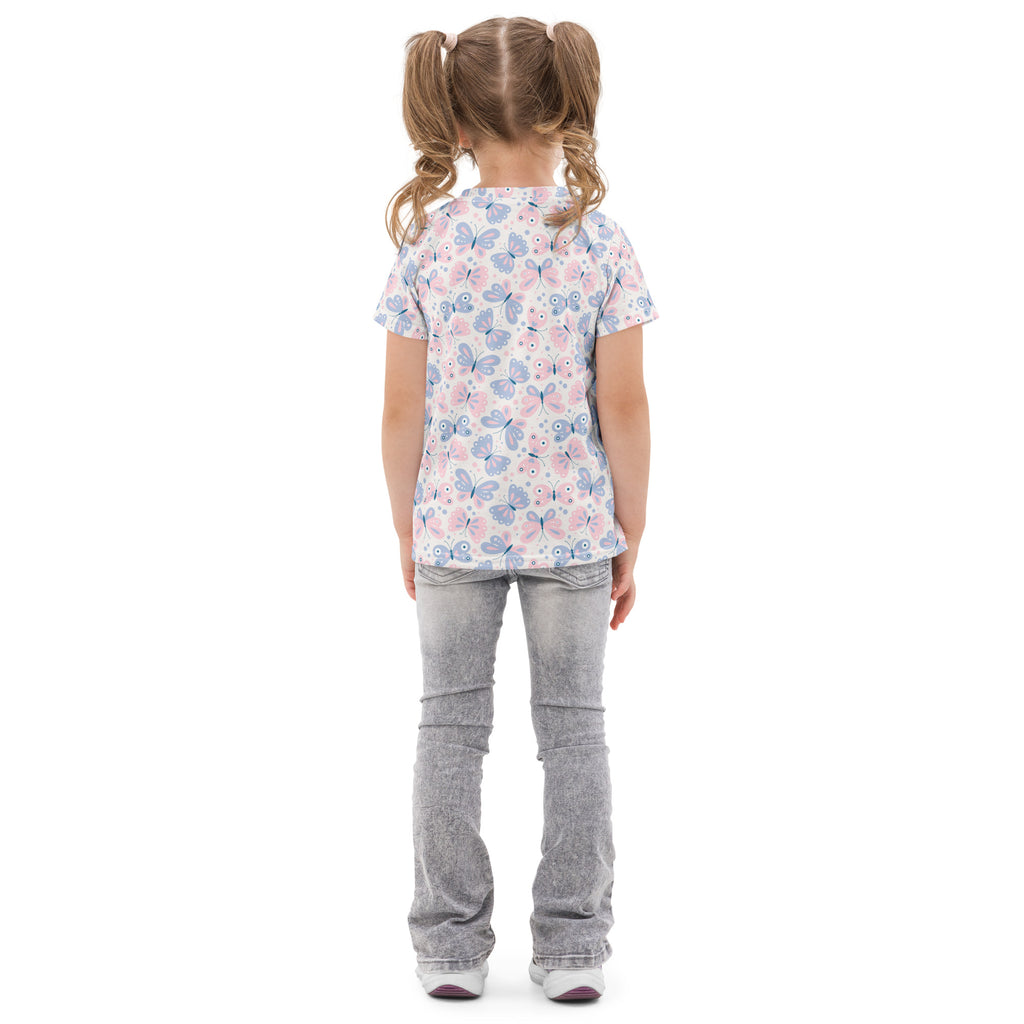 A girl wearing a girls pastel butterfly cotton t-shirt with soft pink and blue butterflies paired with light-wash jeans