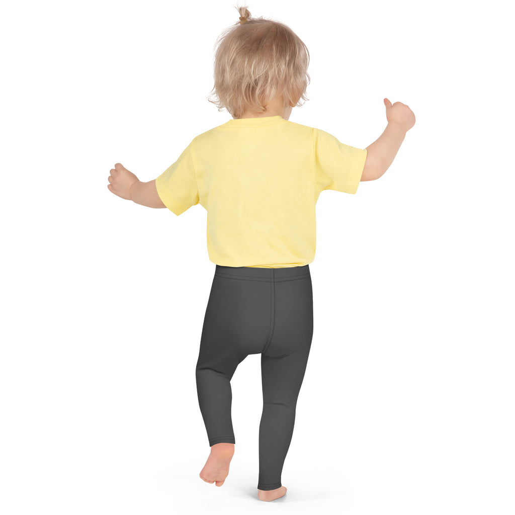 A toddler wearing bright yellow short-sleeved tee and dark gray buttery soft kids leggings from front view
