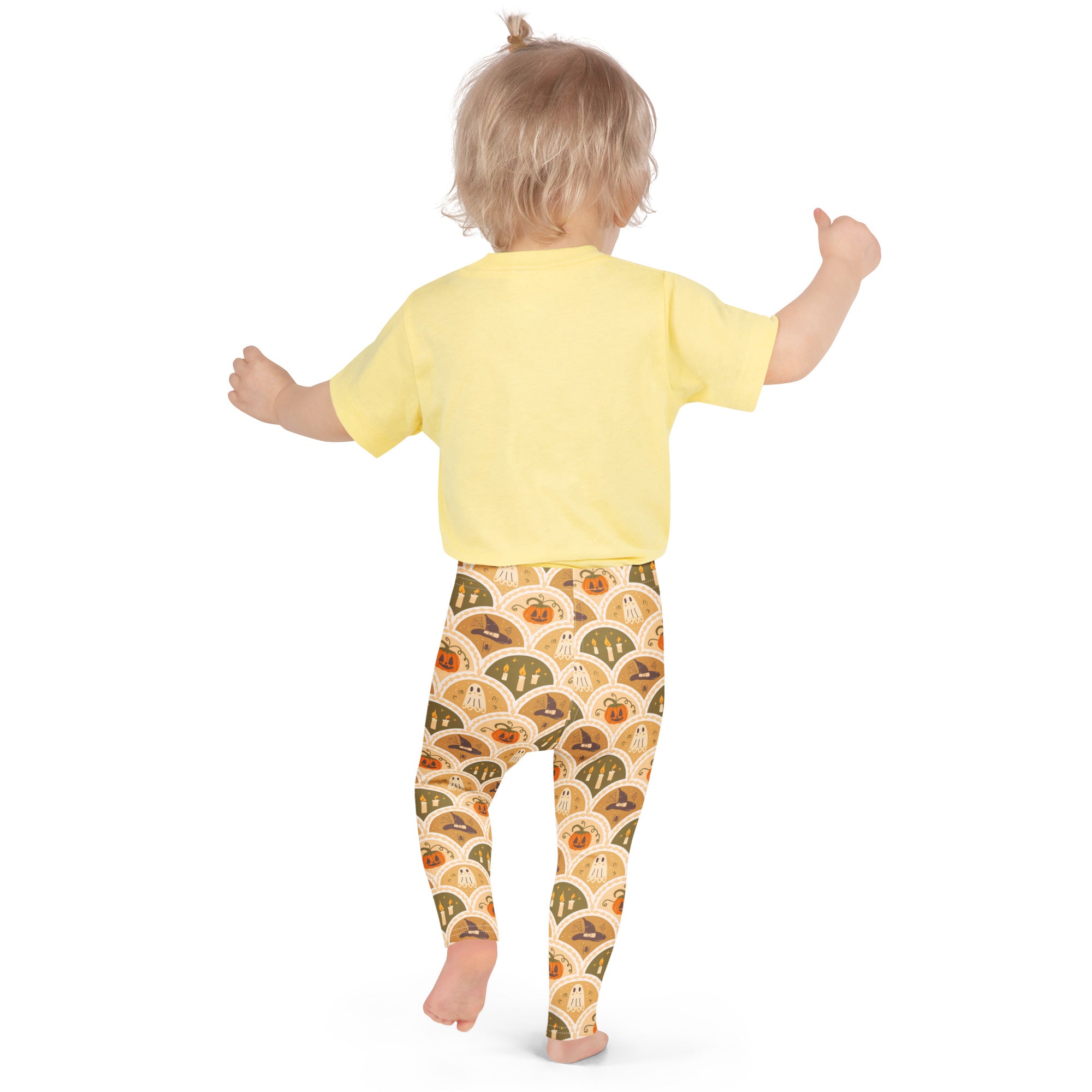 Kids autumn themed halloween buttery soft leggings in orange and beige with pumpkins ghosts and witches pattern paired with yellow short sleeve shirt