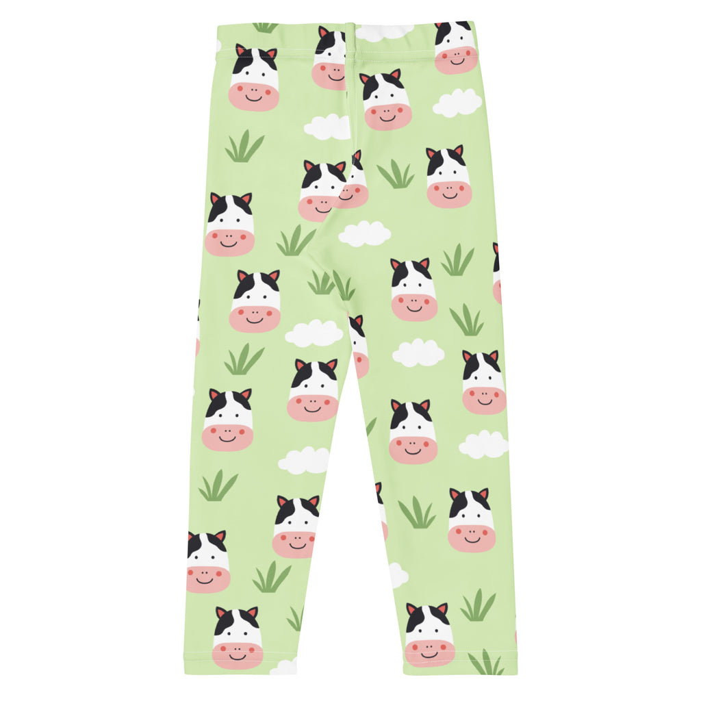Kids cow print buttery soft light green leggings with black and white cartoon cow faces clouds and grass pattern