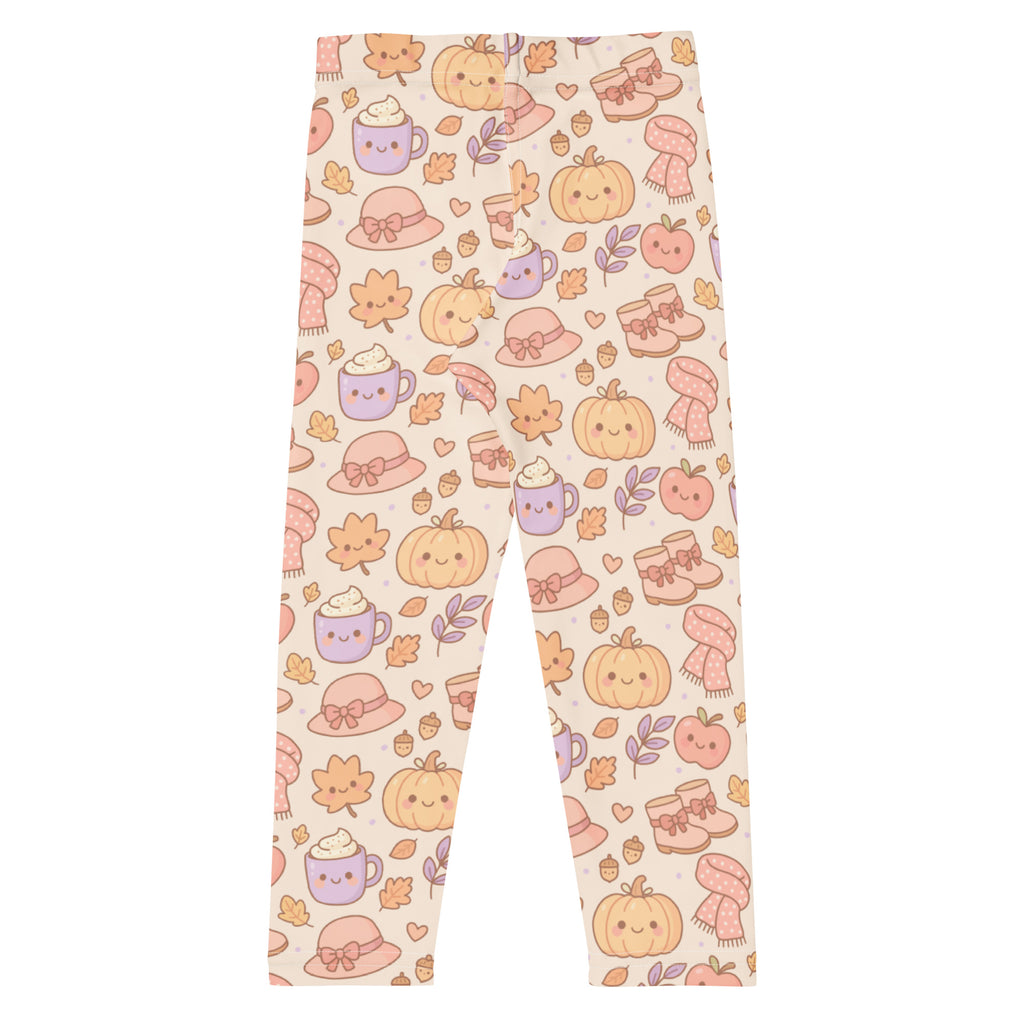 Cream-colored buttery soft kids leggings with playful autumn pattern of smiling pumpkins, cozy hats, and steaming mugs