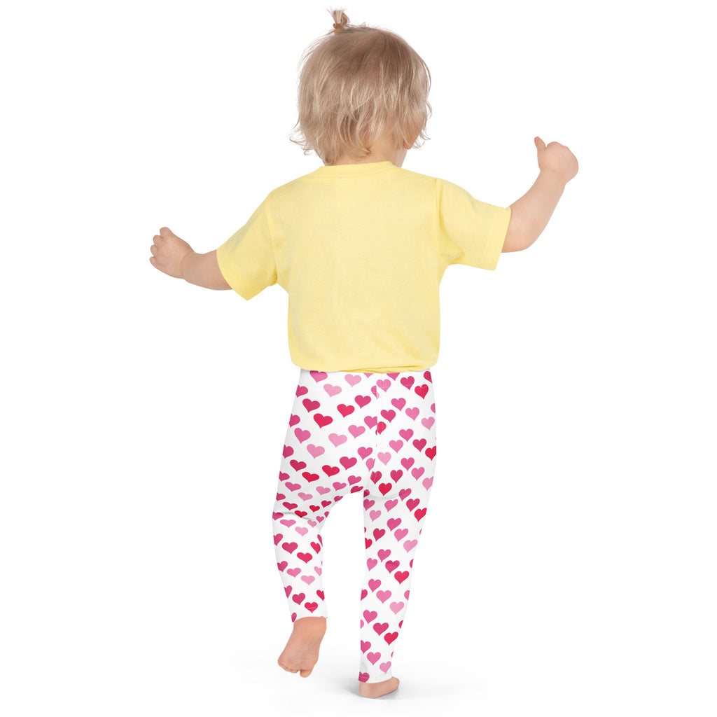 A child wearing girls Valentine’s Day pink heart buttery soft white leggings and a yellow short-sleeved shirt