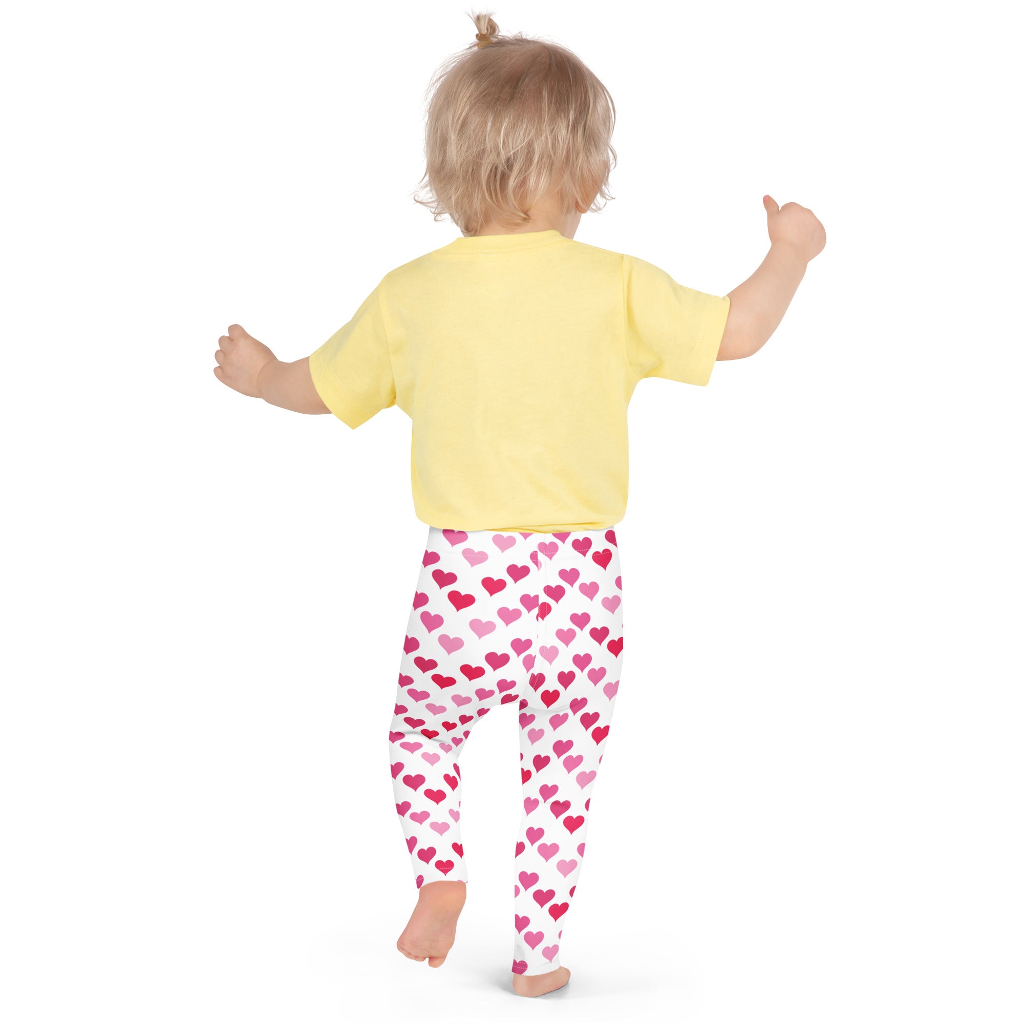 A child wearing girls Valentine’s Day pink heart buttery soft white leggings and a yellow short-sleeved shirt