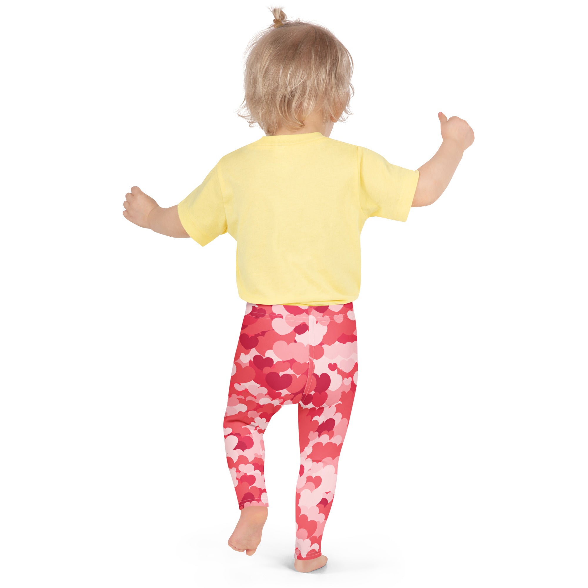 A child wearing buttery soft pink heart cloud leggings with red and pink heart patterns and a yellow short-sleeved shirt