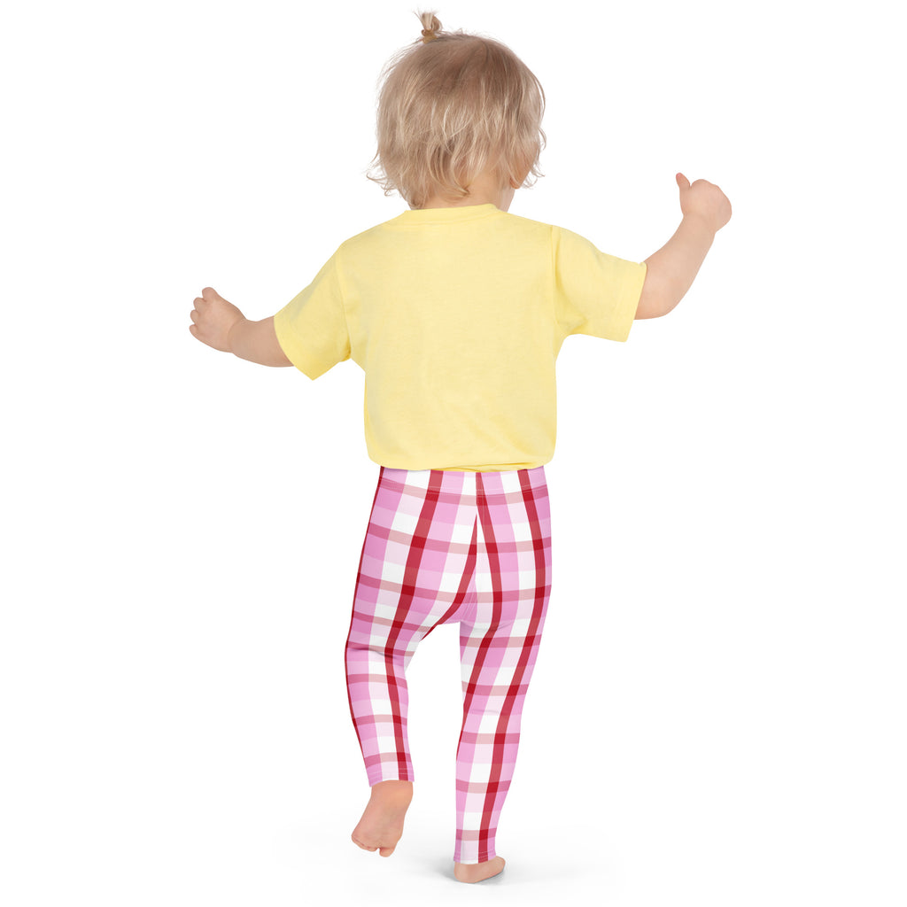 A toddler wearing girls pink and red plaid buttery soft leggings and a yellow short sleeved shirt