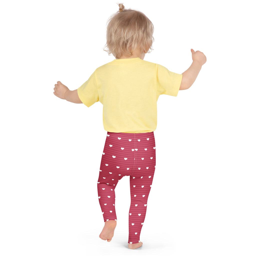 A child wearing girls pink stripe heart leggings buttery soft leggings in red with white hearts and a yellow shirt