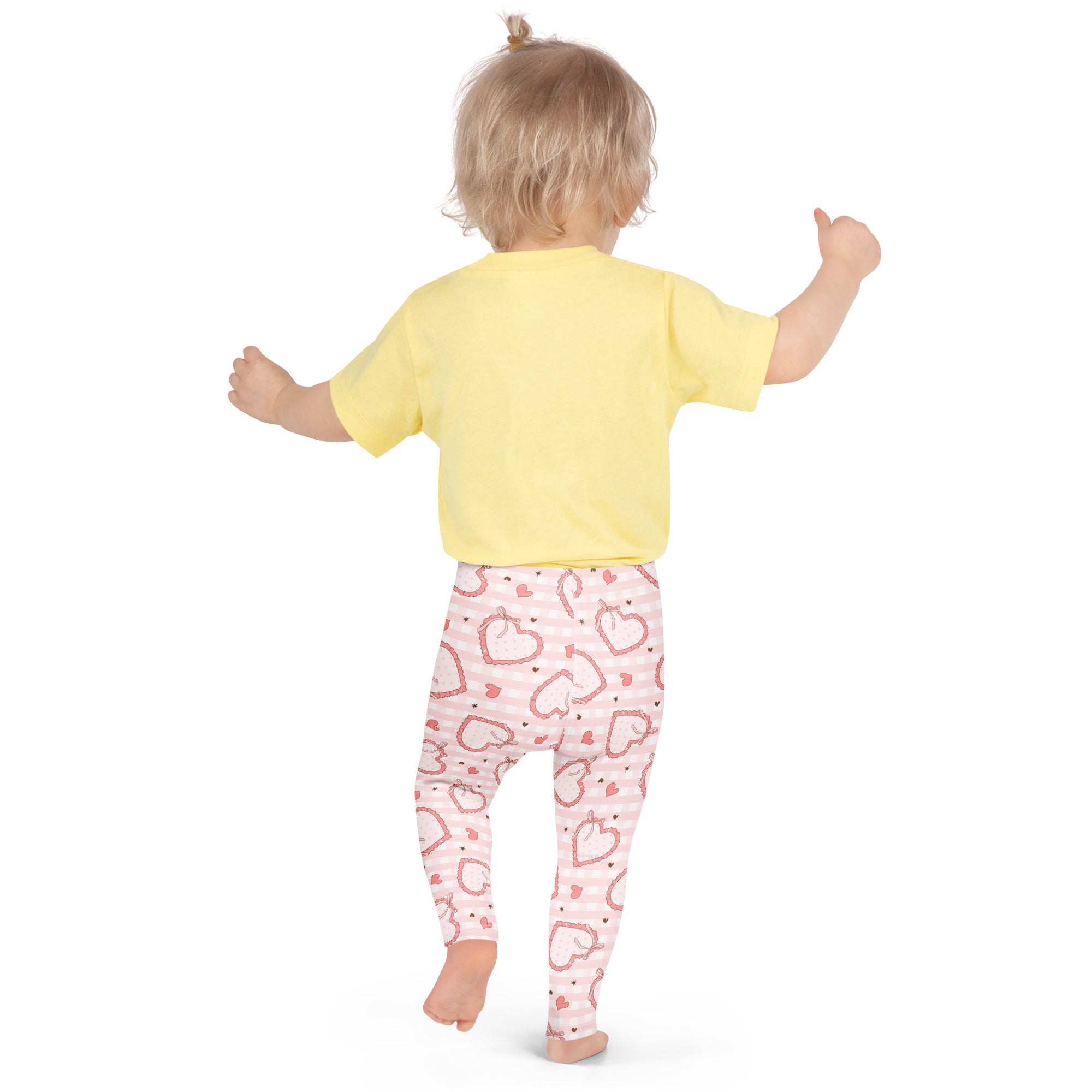 A child wearing girls plaid bow heart buttery soft leggings in pink with white stripes and red heart patterns
