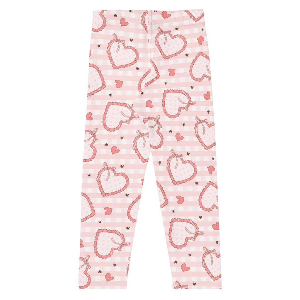 Girls plaid bow heart leggings in pink with heart pattern on buttery soft fabric against pastel gingham background
