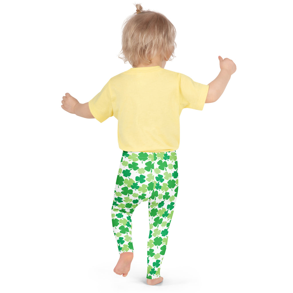 A child wearing girls green shamrock buttery soft leggings and a yellow short-sleeved shirt standing front view