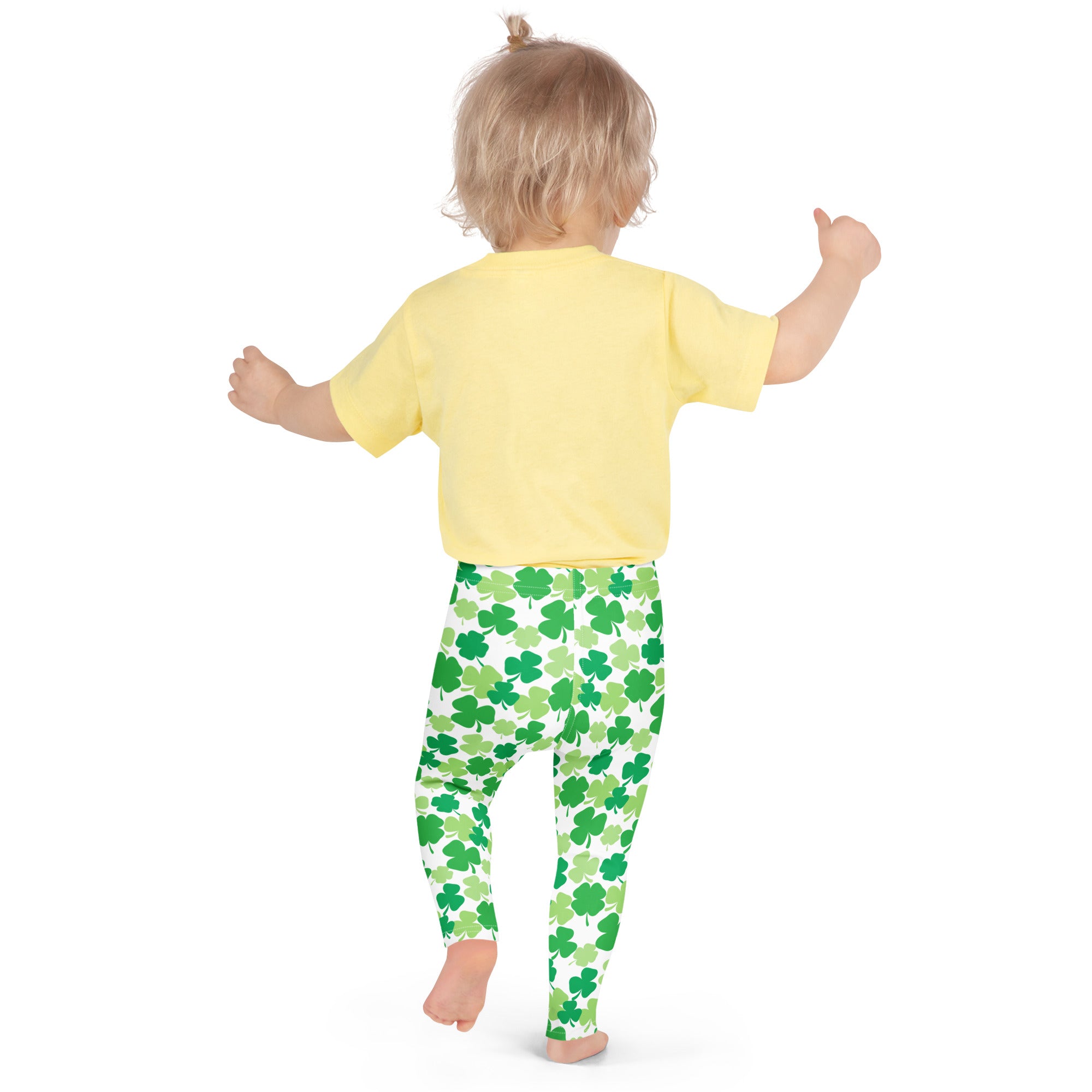 A child wearing girls green shamrock buttery soft leggings and a yellow short-sleeved shirt standing front view