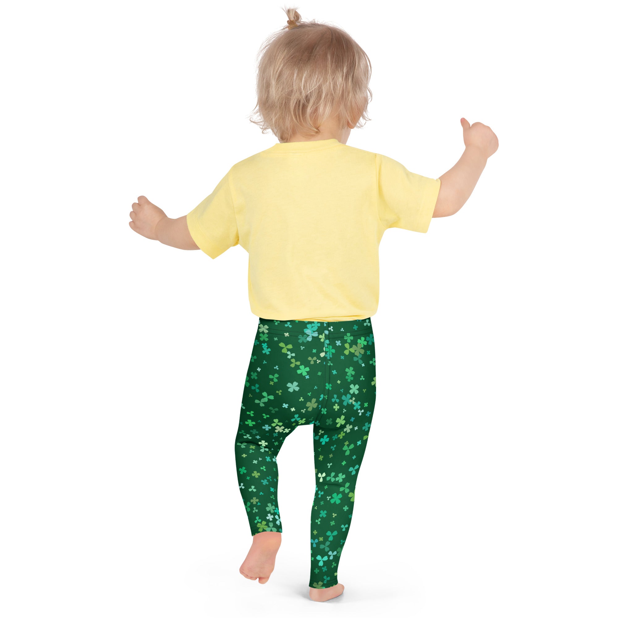 A child wearing girls teal and green shamrock buttery soft leggings in green with a shamrock pattern and yellow shirt