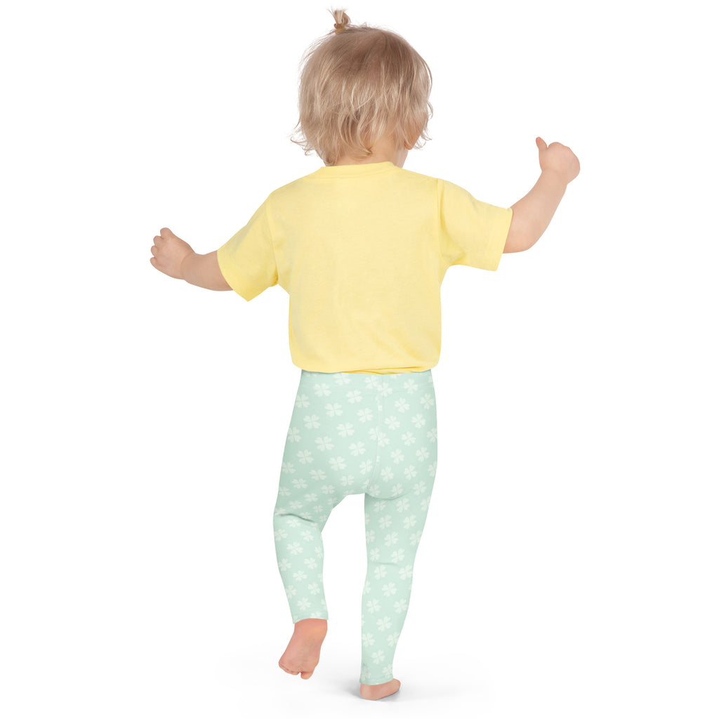 A toddler wearing girls mint shamrock buttery soft leggings in light mint green with white floral patterns and a yellow top