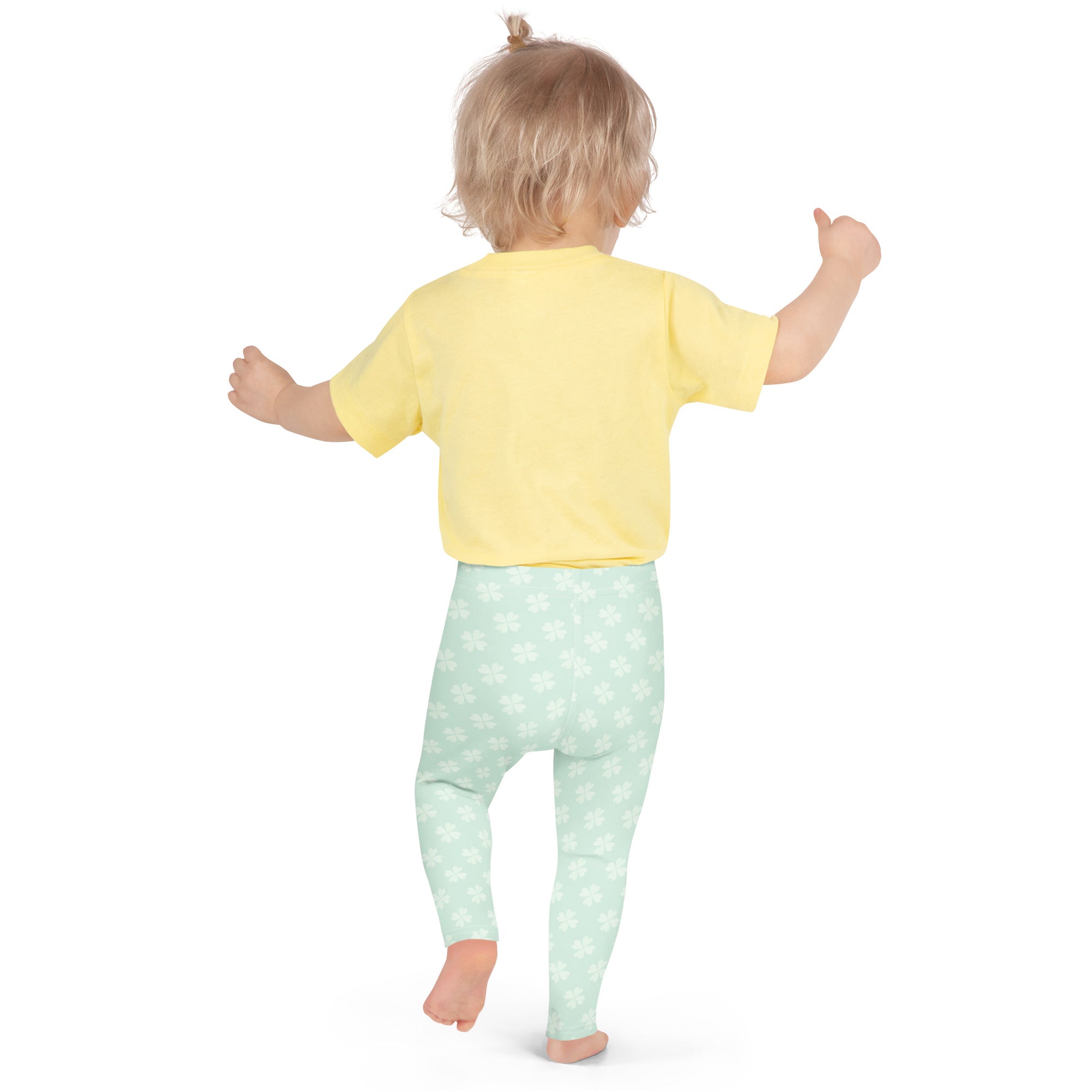 A toddler wearing girls mint shamrock buttery soft leggings in light mint green with white floral patterns and a yellow top