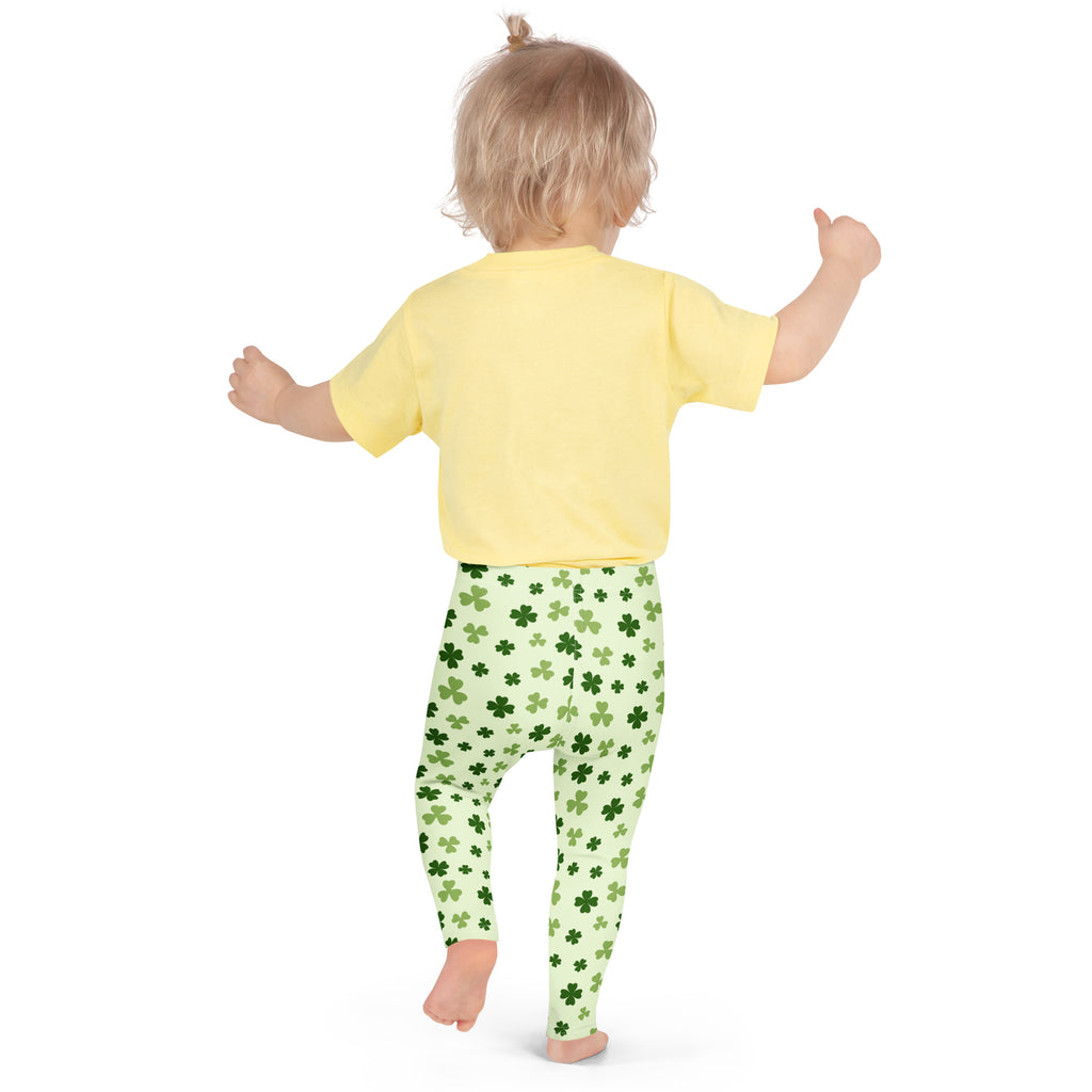 A child wearing girls light green shamrock buttery soft leggings with dark green shamrock patterns and a yellow shirt
