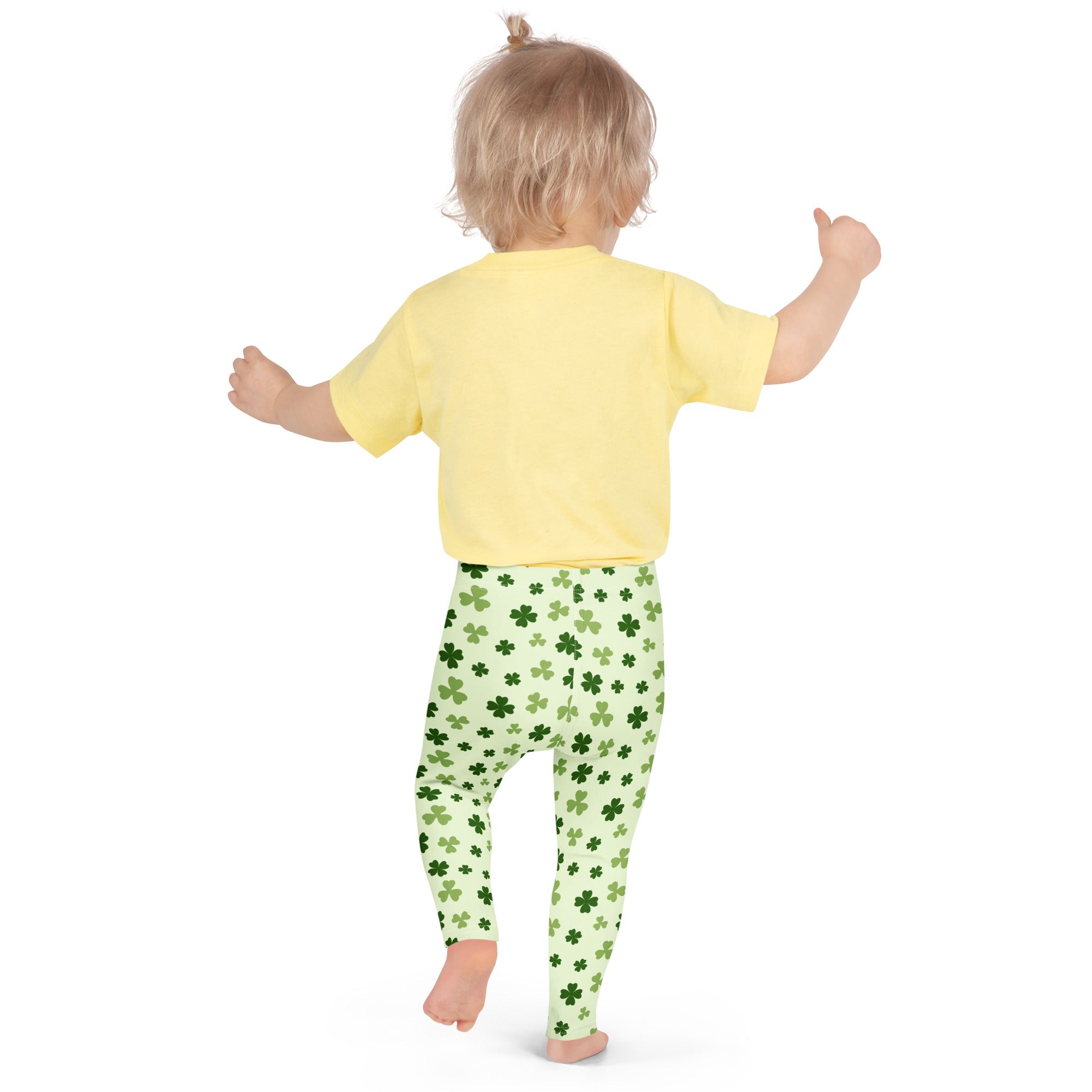 A child wearing girls light green shamrock buttery soft leggings with dark green shamrock patterns and a yellow shirt
