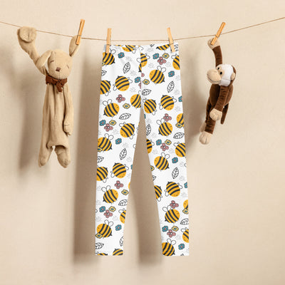 White kids leggings with yellow bee and flower print, hanging between plush toys.