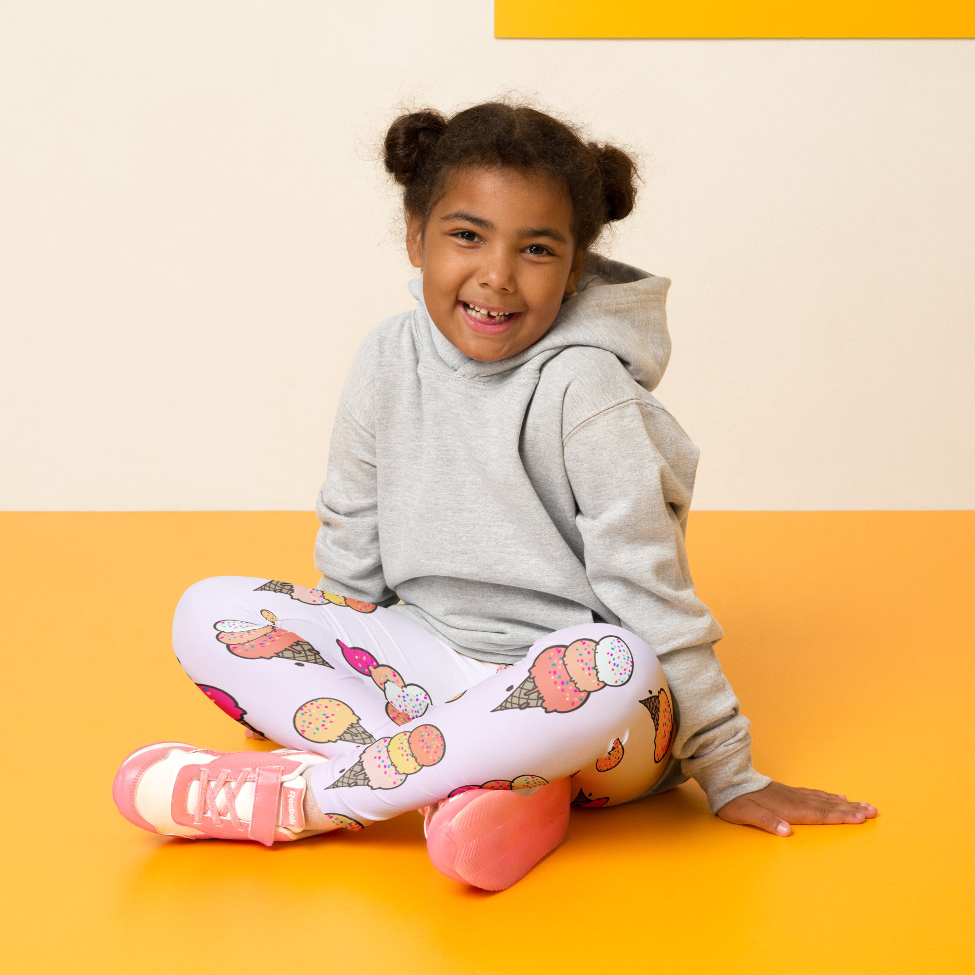 Smiling girl in gray hoodie and white kids leggings with colorful ice cream print