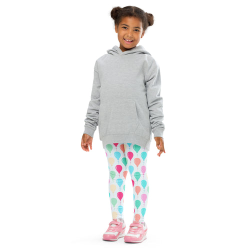 Girl wearing gray hooded sweatshirt with front pocket and colorful birthday balloon patterned leggings