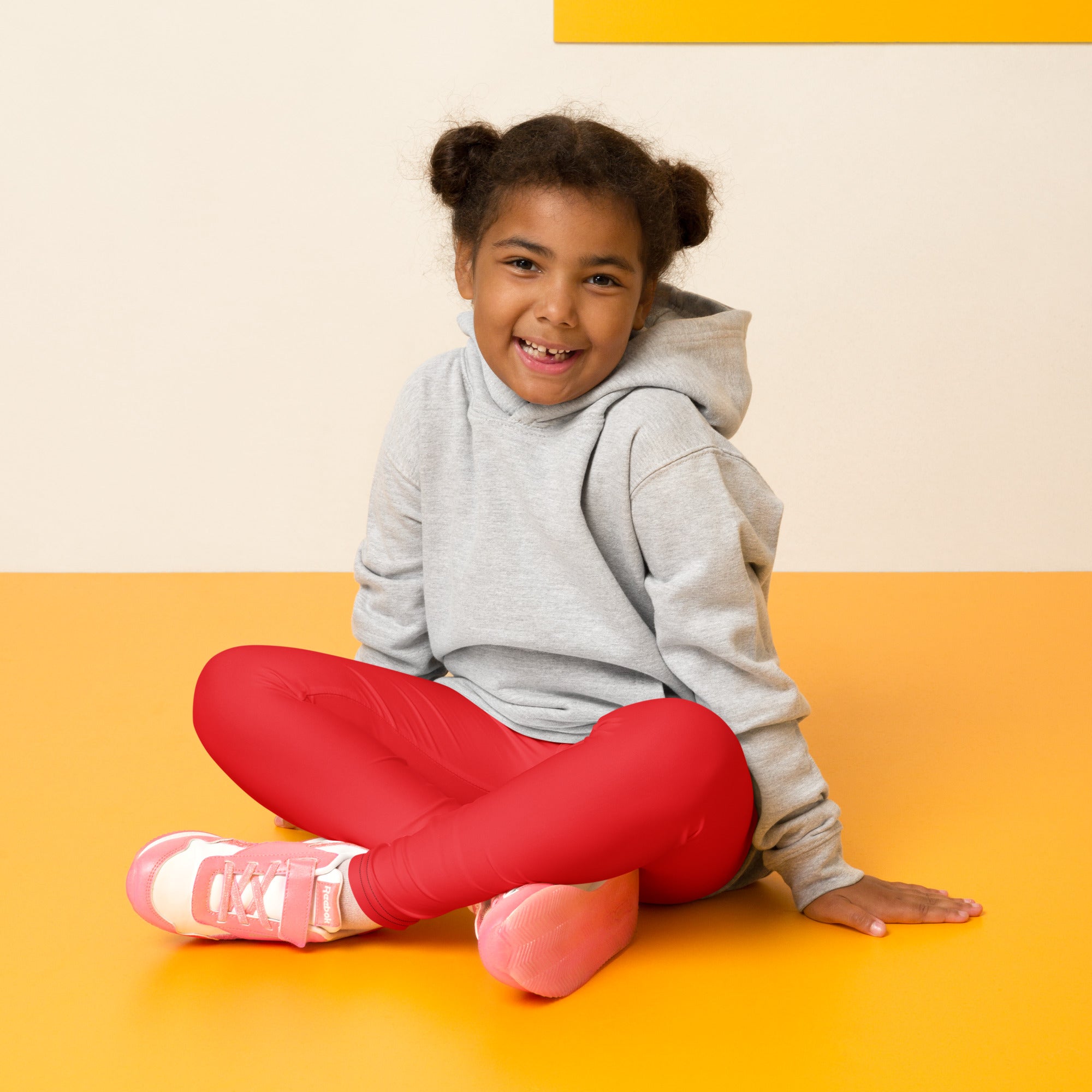 Pink and white athletic sneakers with velcro straps paired with kids buttery soft red leggings for active wear