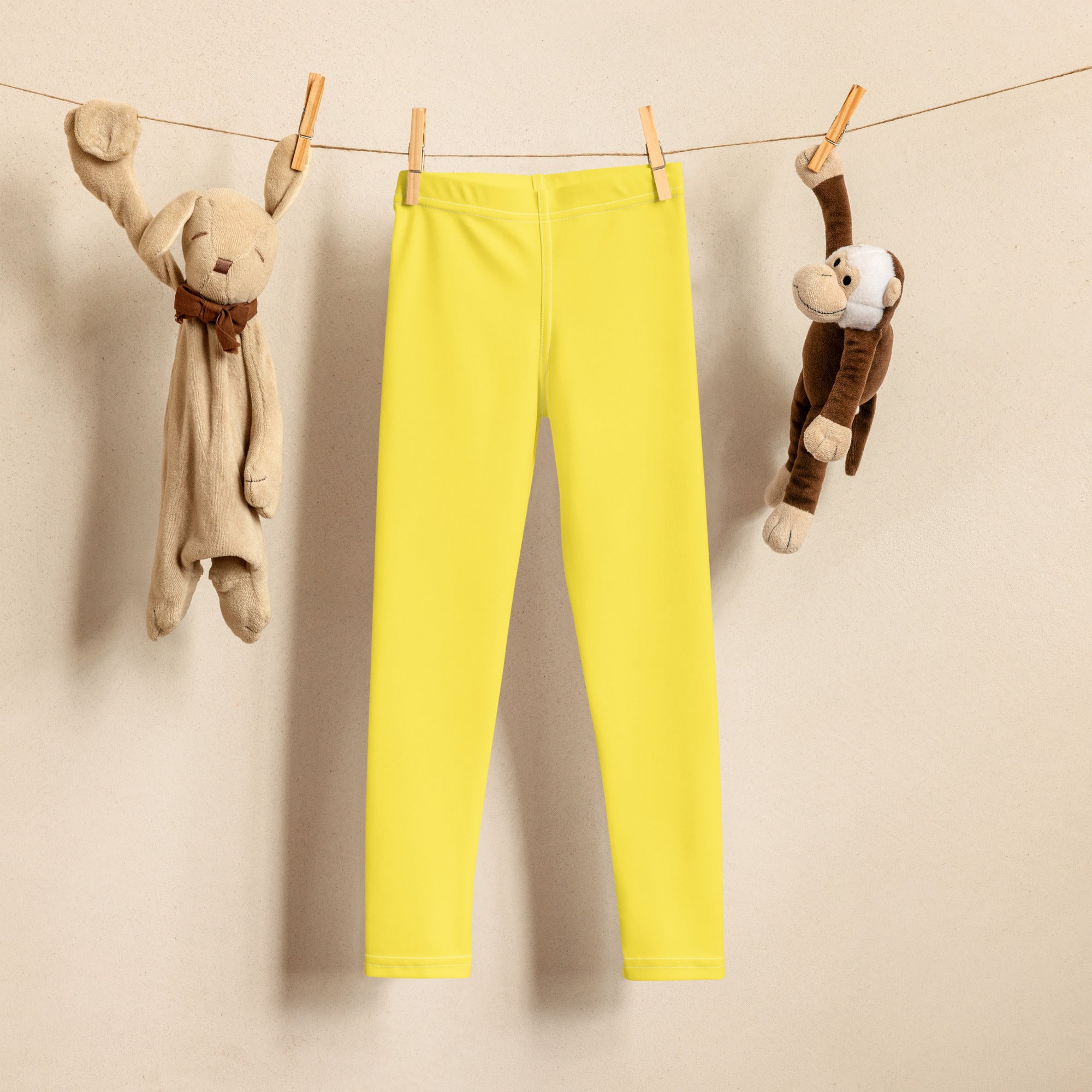 Kids buttery soft yellow leggings hanging on a clothesline showcasing bright yellow buttery soft fabric