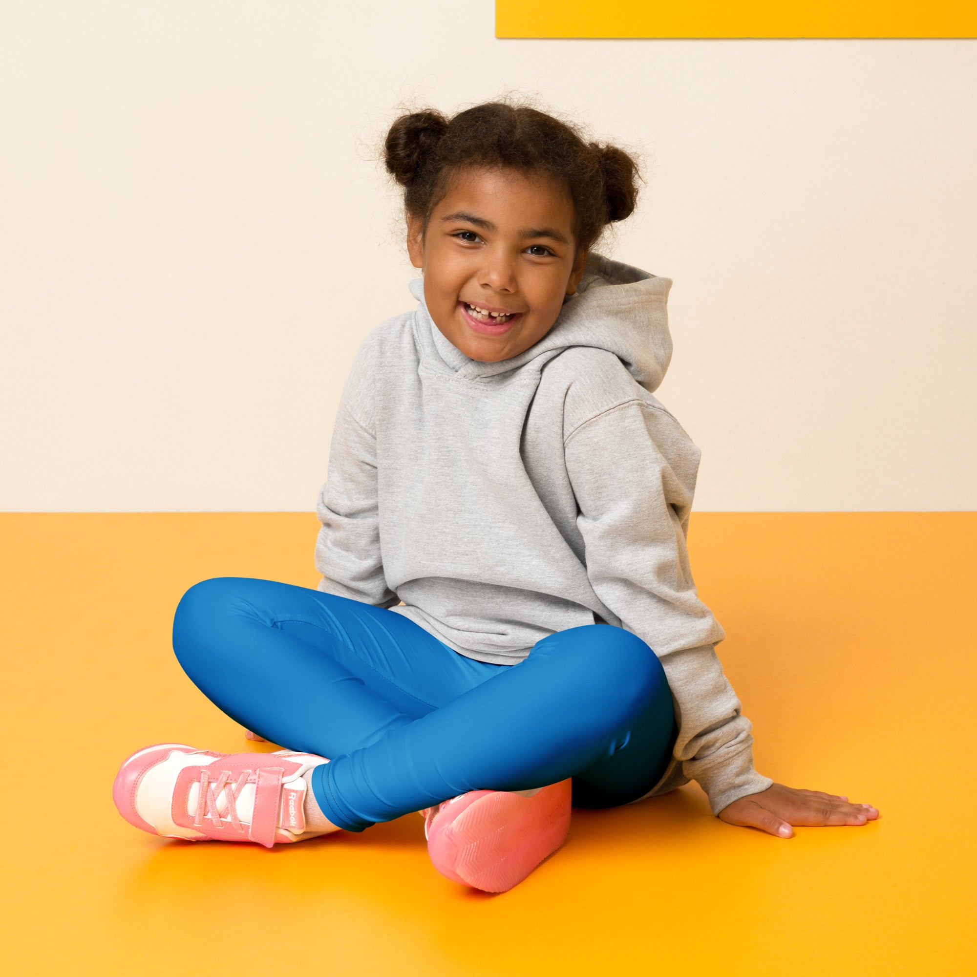 Child wearing buttery soft blue leggings paired with a gray hoodie and pink sneakers standing outdoors