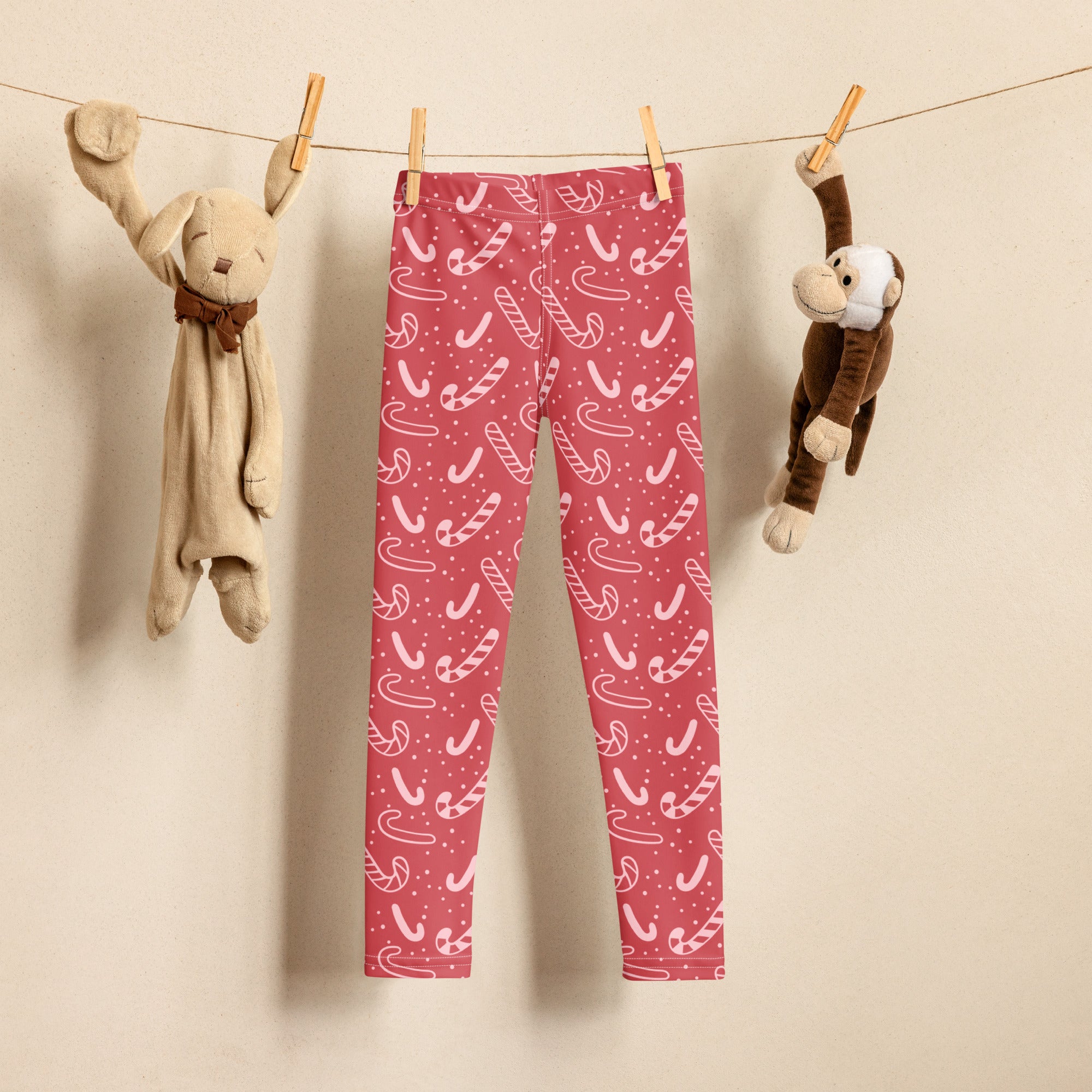 Girls red candy cane buttery soft leggings with white candy cane pattern hanging on a clothesline