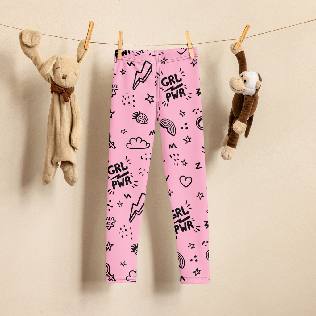 Pink buttery soft kids leggings with black grl pwr text and cartoon graphics hanging on a clothesline