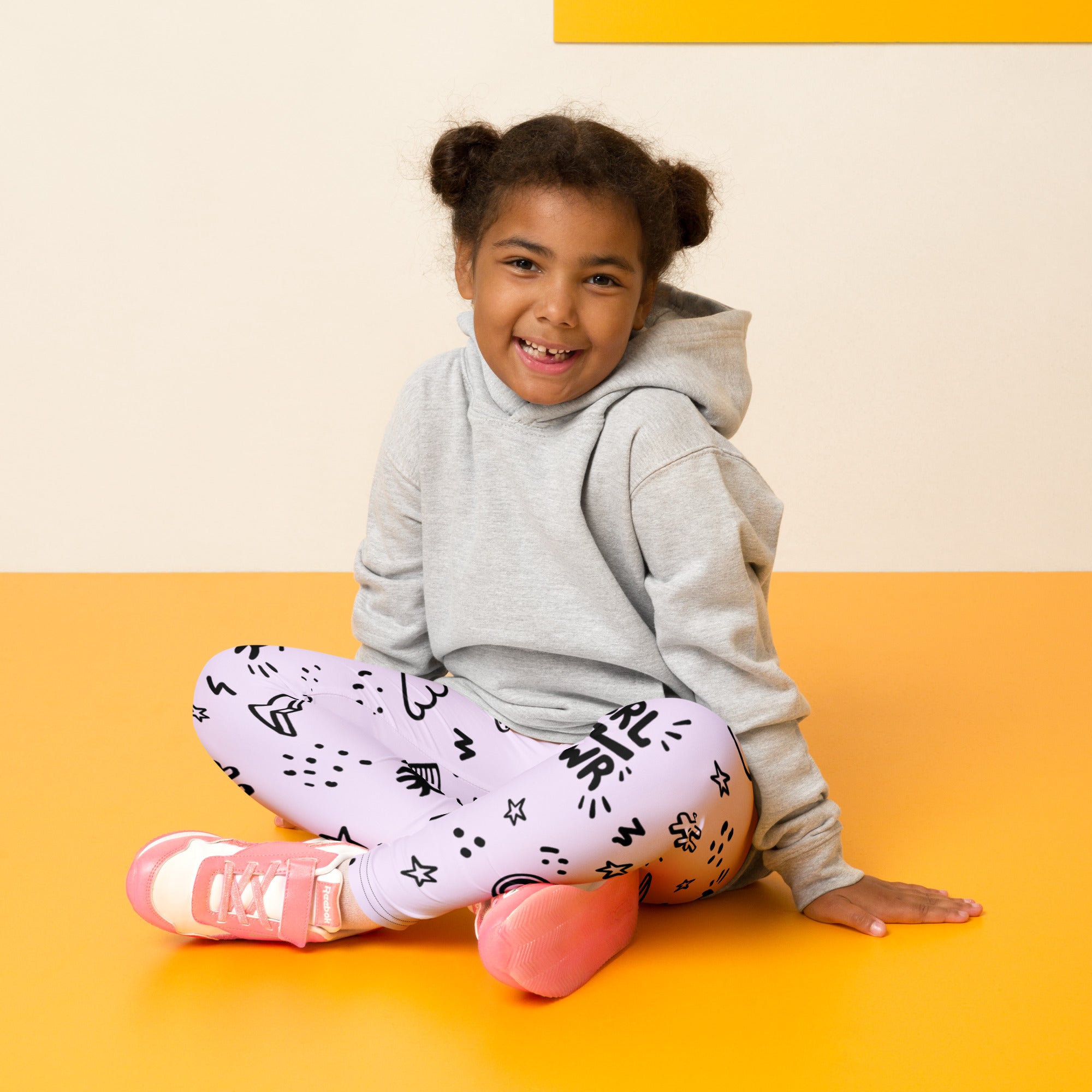 A child wearing girl power kids buttery soft gray hoodie and lavender leggings with black doodle patterns and pink sneakers