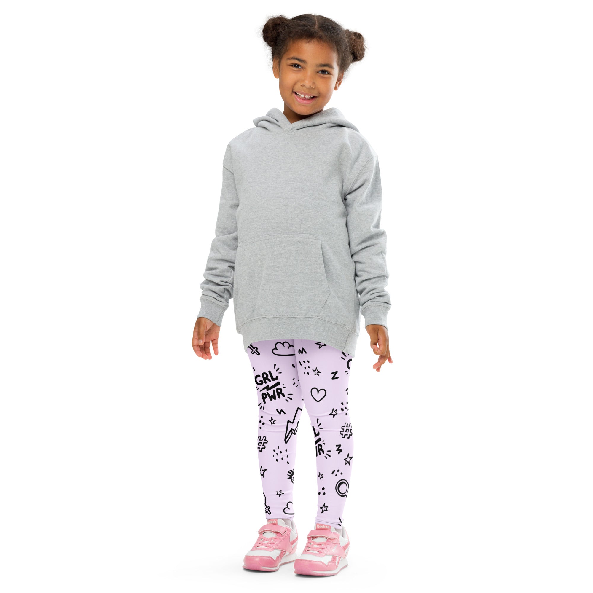 A young girl wearing girl power kids buttery soft lavender leggings with black graphic prints and pink sneakers