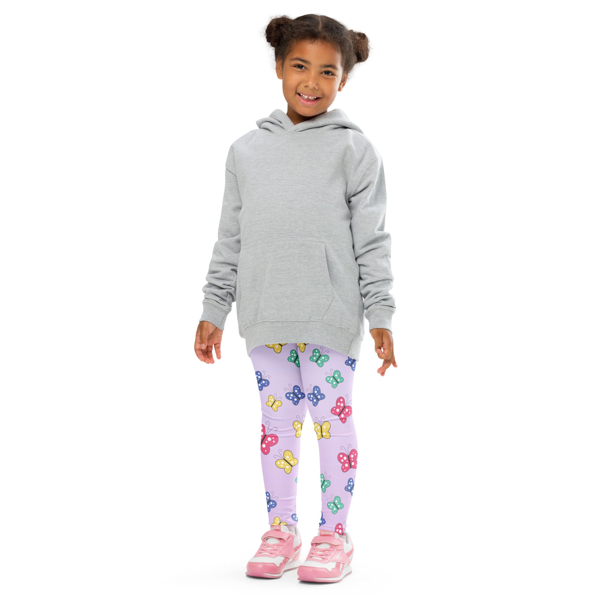 A child wearing colorful butterflies buttery soft leggings in lavender paired with a light gray hooded sweatshirt and pink sneakers