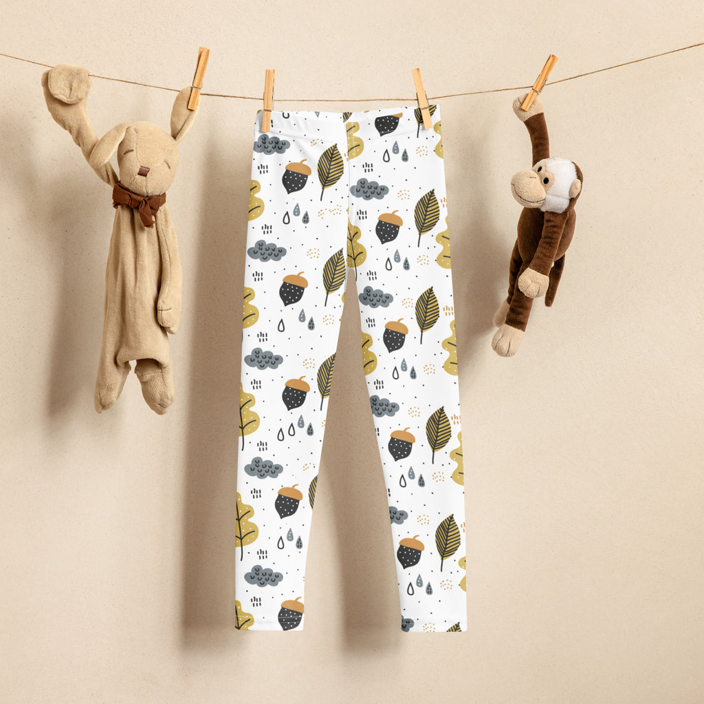 White buttery soft kids leggings with a fall-themed acorn leaf and cloud pattern in green brown and gray shades