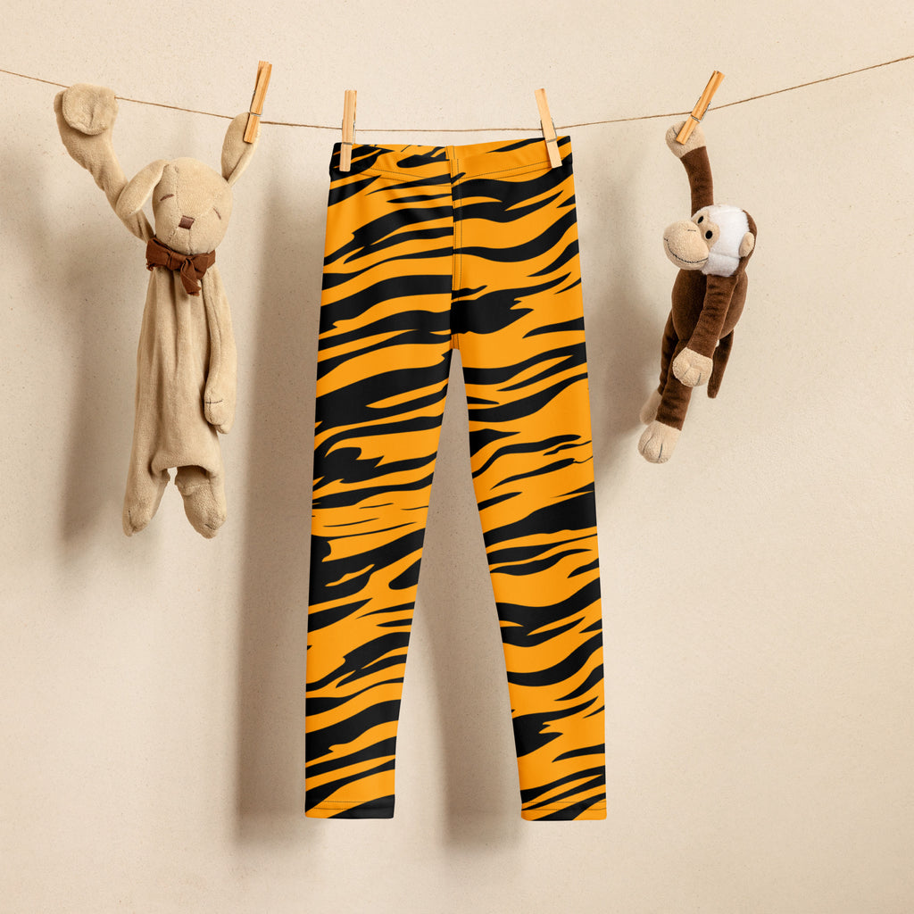 Kids tiger stripe buttery soft leggings in bright orange and black hanging on a clothesline for everyday wear
