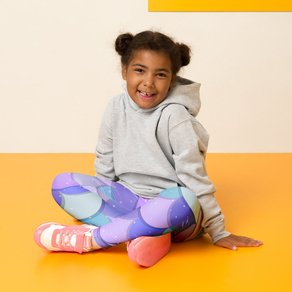 A child wearing girls purple mermaid buttery soft leggings in galaxy pattern with purple blue and pink hues and a gray hoodie