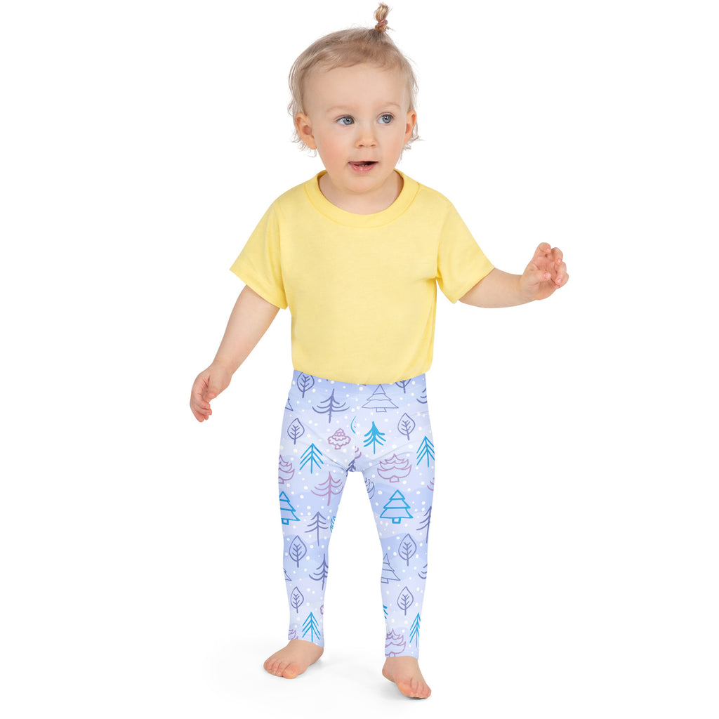 A child wearing kids snowy forest winter buttery soft leggings in light blue with teal and purple tree and snowflake patterns