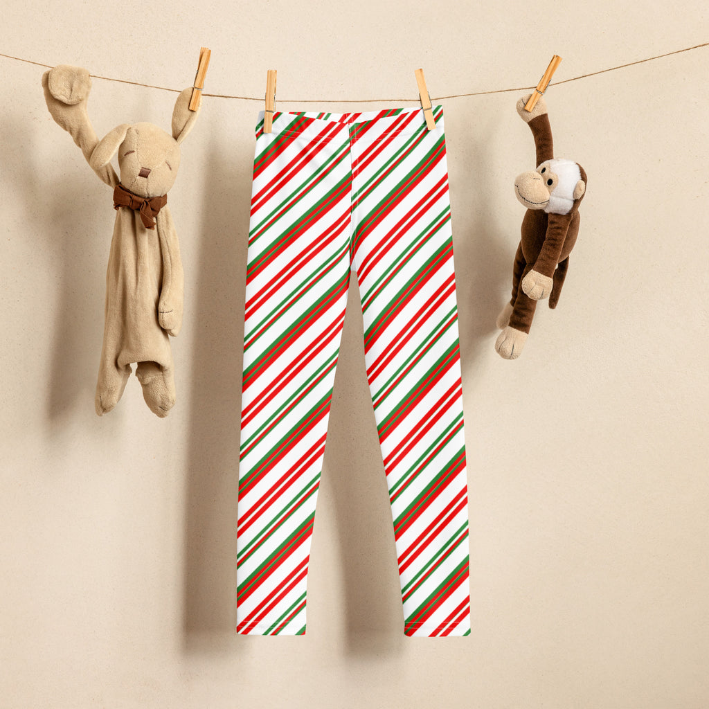 Kids peppermint candy cane striped buttery soft leggings in red green and white hanging on a clothesline