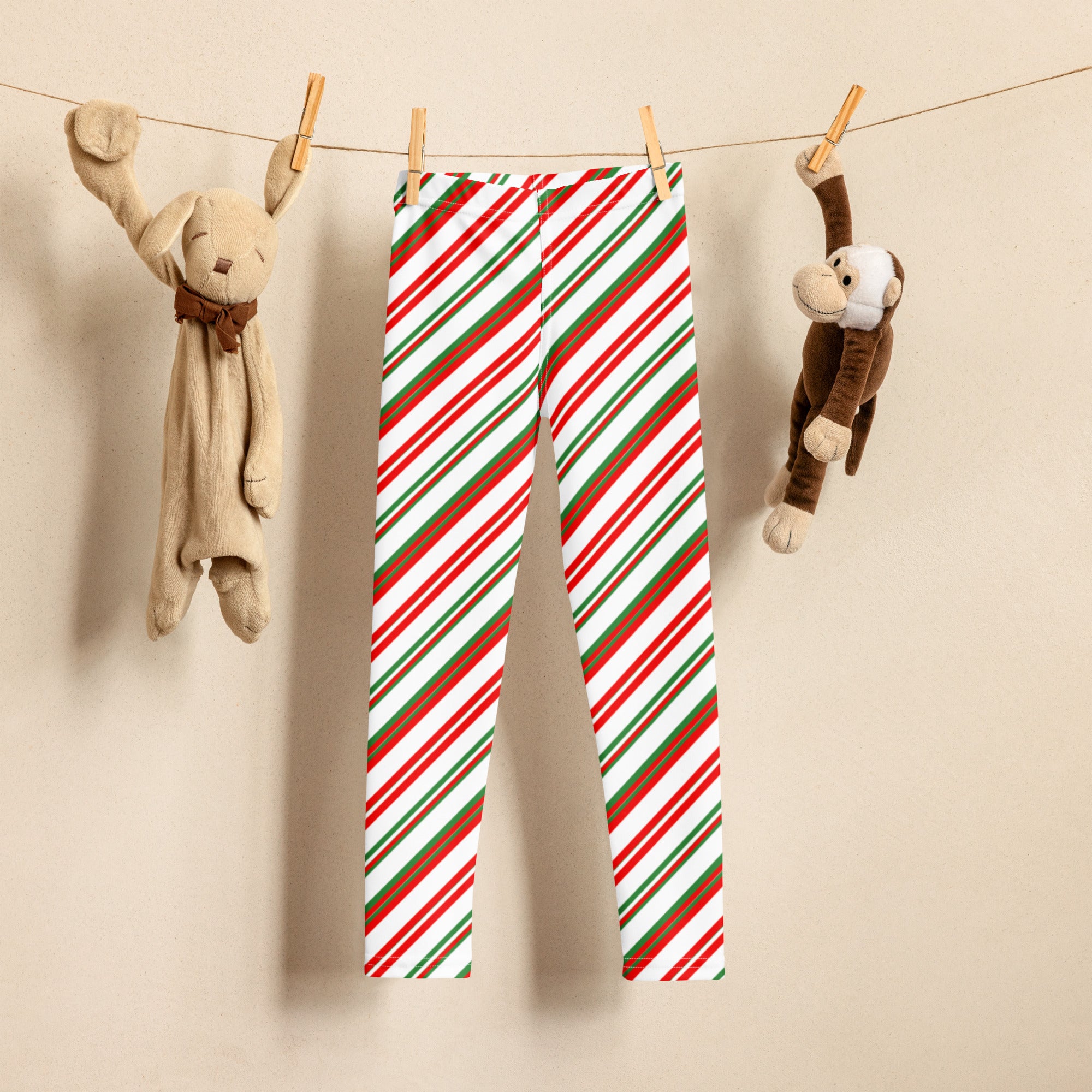 Kids peppermint candy cane striped buttery soft leggings in red green and white hanging on a clothesline