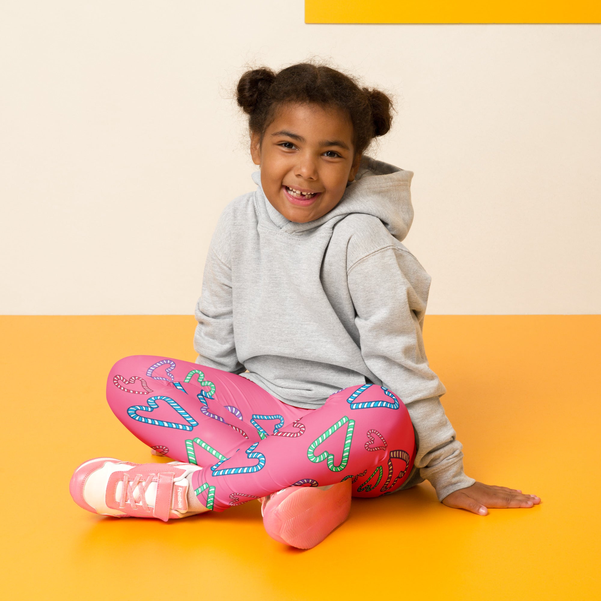 Girls pink buttery soft leggings with colorful candy cane heart patterns perfect for festive wear