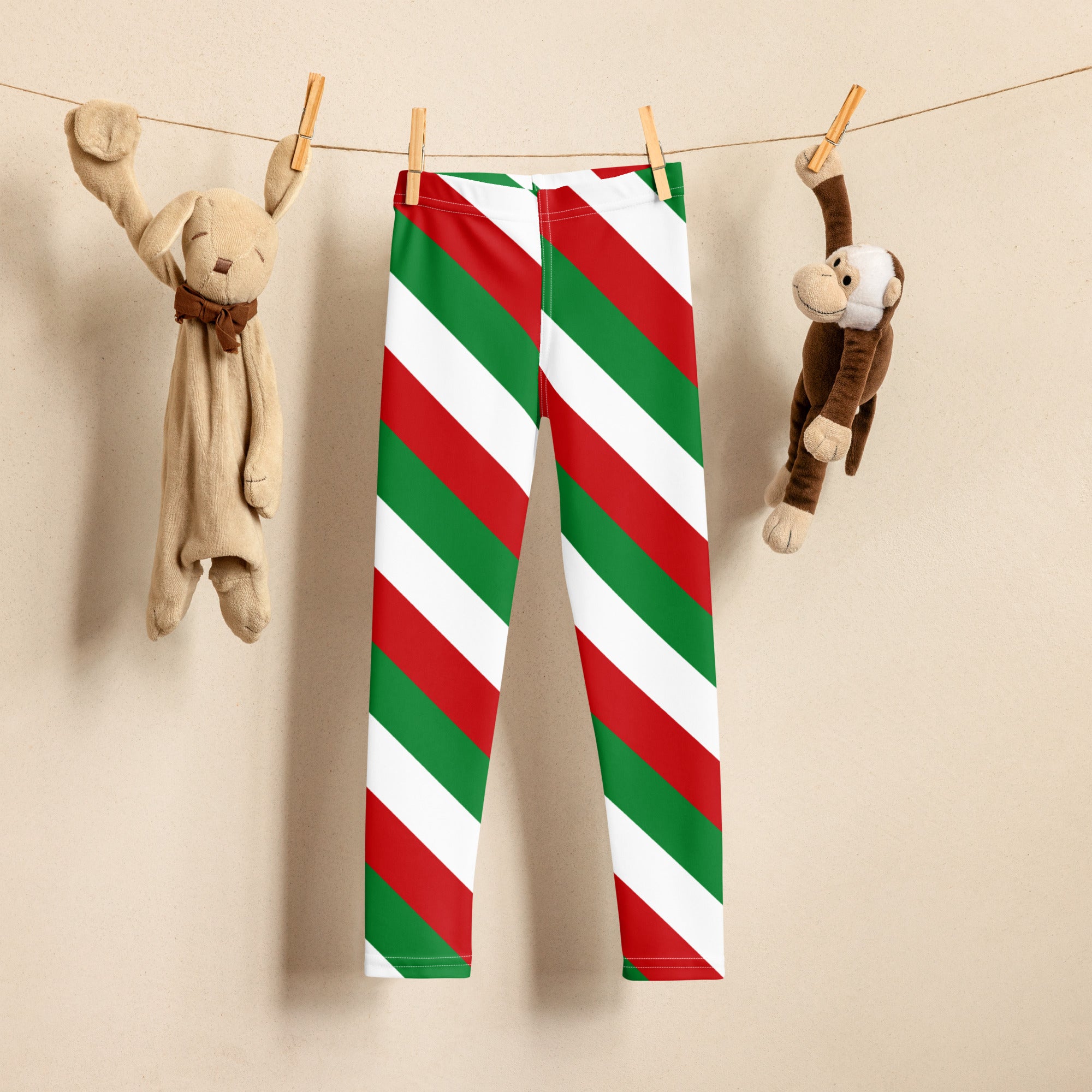Kids red green and white Christmas buttery soft leggings with diagonal stripes hanging on a clothesline