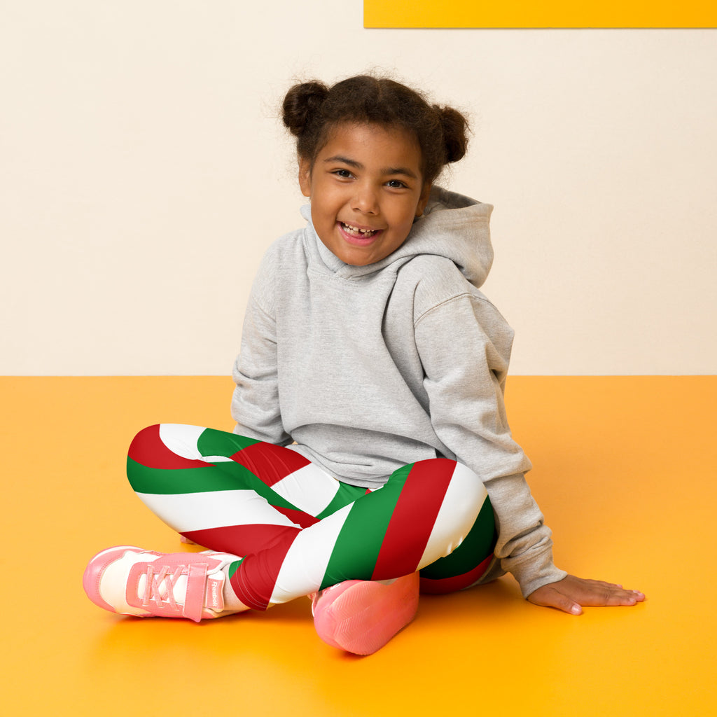 Child wearing kids red green and white Christmas buttery soft leggings with festive striped pattern