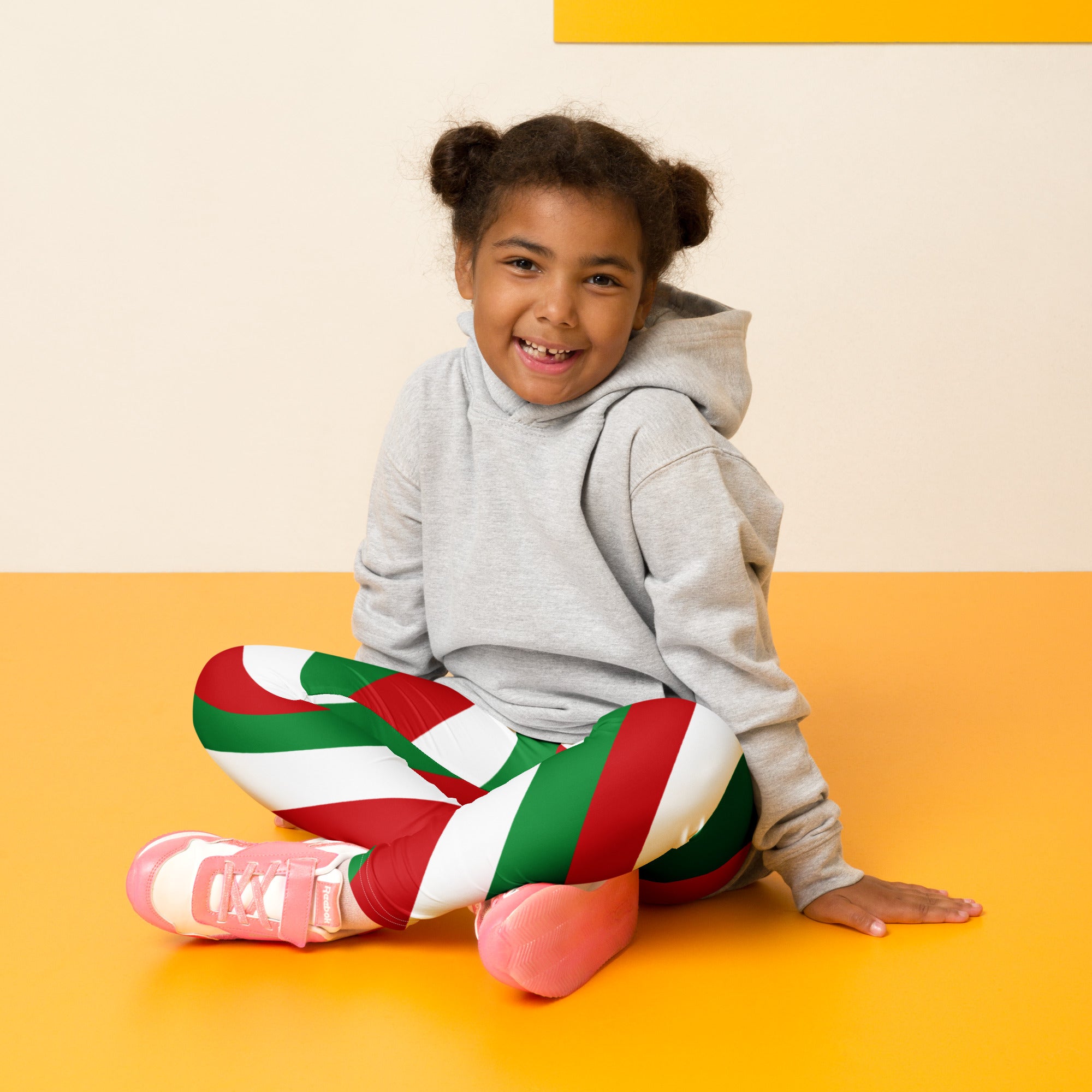 Child wearing kids red green and white Christmas buttery soft leggings with festive striped pattern
