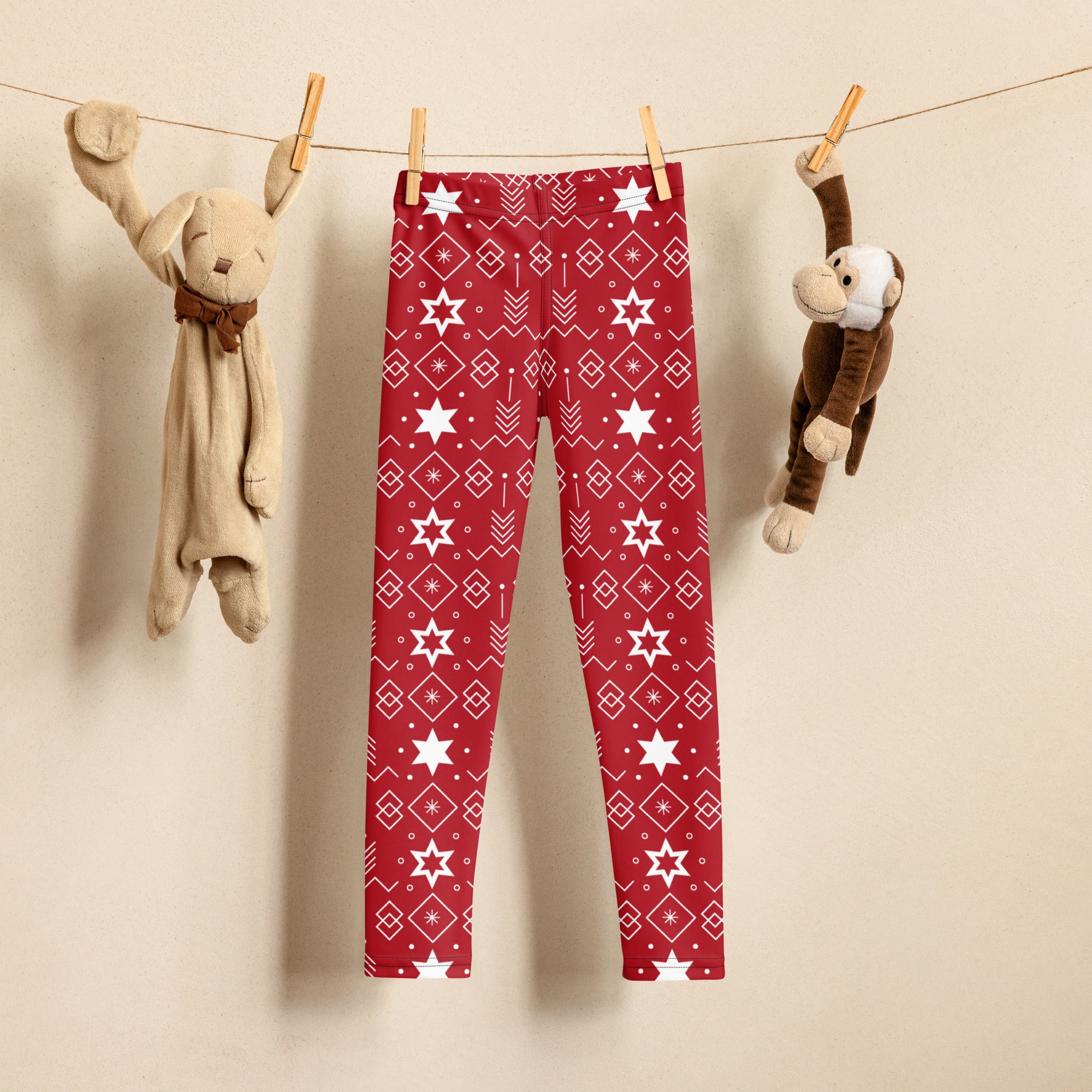 Kids red hanukkah star of david buttery soft leggings with white geometric and star pattern hanging on a clothesline