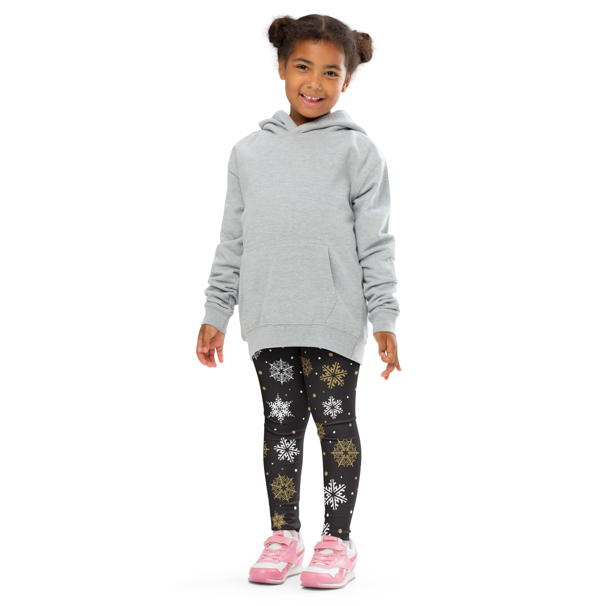 A child wearing black kids gold and white snowflake buttery soft leggings and a light gray hooded sweatshirt
