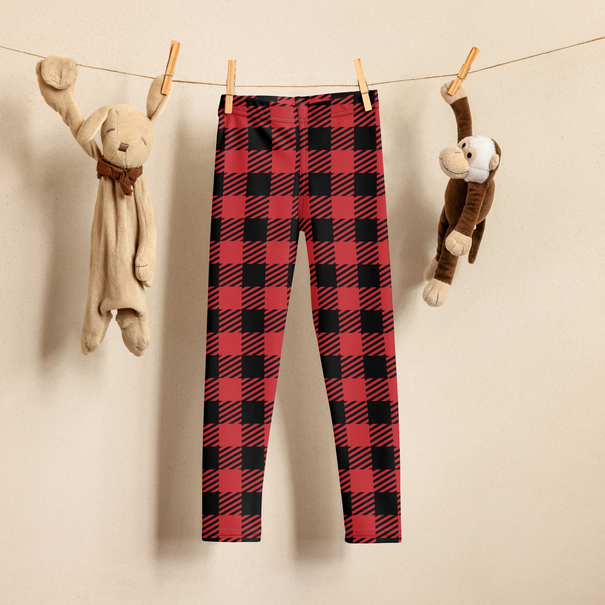 Kids red buffalo plaid buttery soft leggings in red and black hanging on a clothesline
