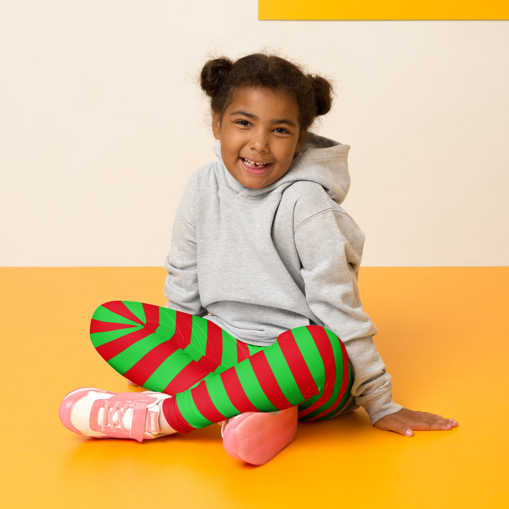 A child wearing kids red and green striped Christmas buttery soft leggings with a playful candy cane pattern