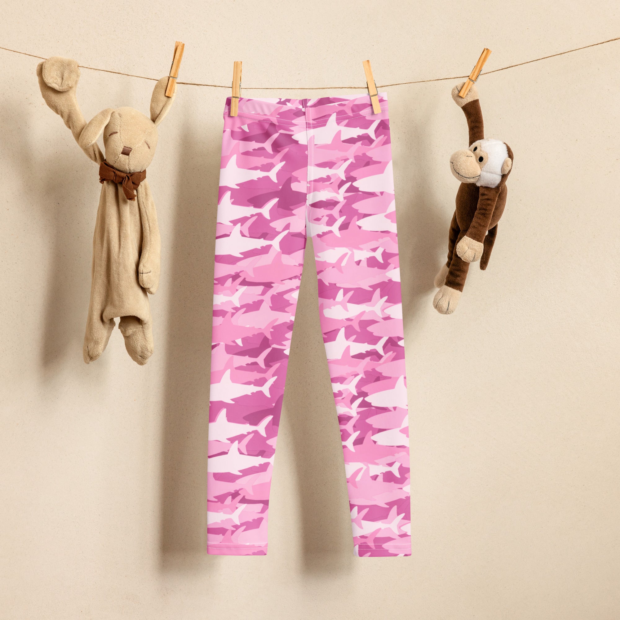 Girls pink shark buttery soft leggings in pink and white camouflage hanging on a clothesline