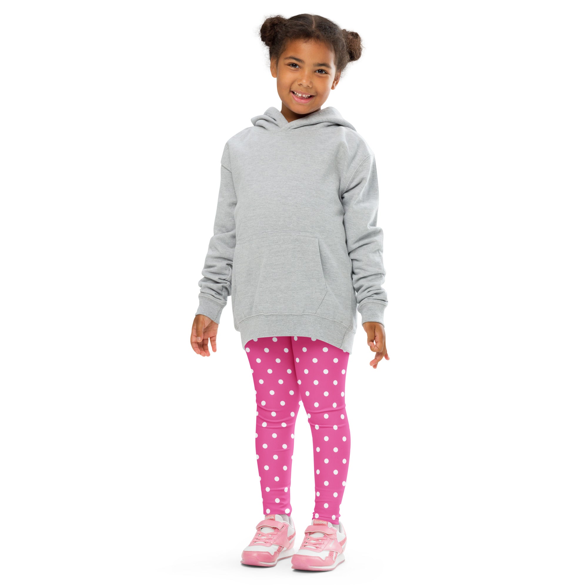 A young girl wearing girls pink polka dot buttery soft leggings made of bright pink fabric with white dots