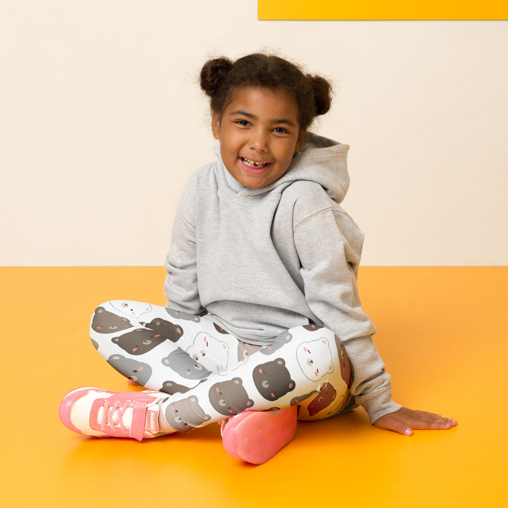 A child wearing buttery soft kids bear face pattern leggings in white with cartoon bears and a gray hoodie