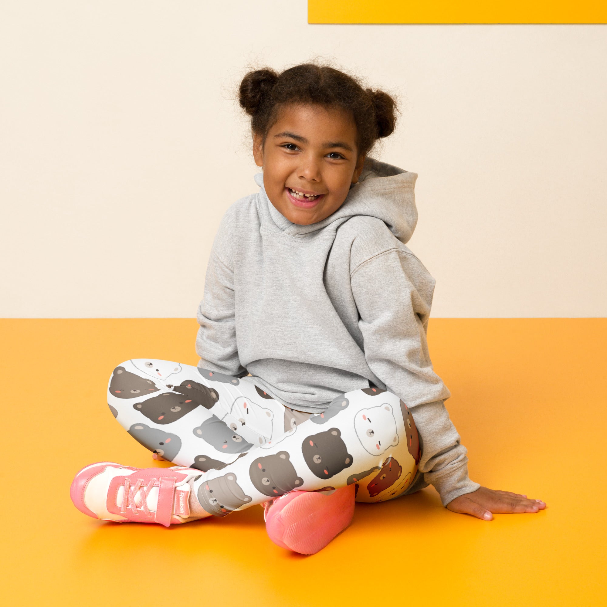 A child wearing buttery soft kids bear face pattern leggings in white with cartoon bears and a gray hoodie